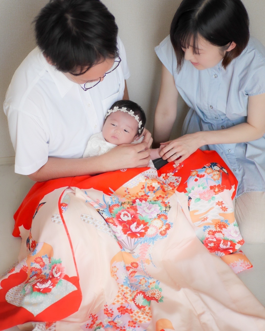 東京都内のご自宅で撮影されたお宮参り後のニューボーンフォト。パパとママに抱っこされ、美しい産着を身にまとった赤ちゃんのかわいらしい一枚。家族の温かな絆と赤ちゃんの可愛らしさが感じられる特別な瞬間。