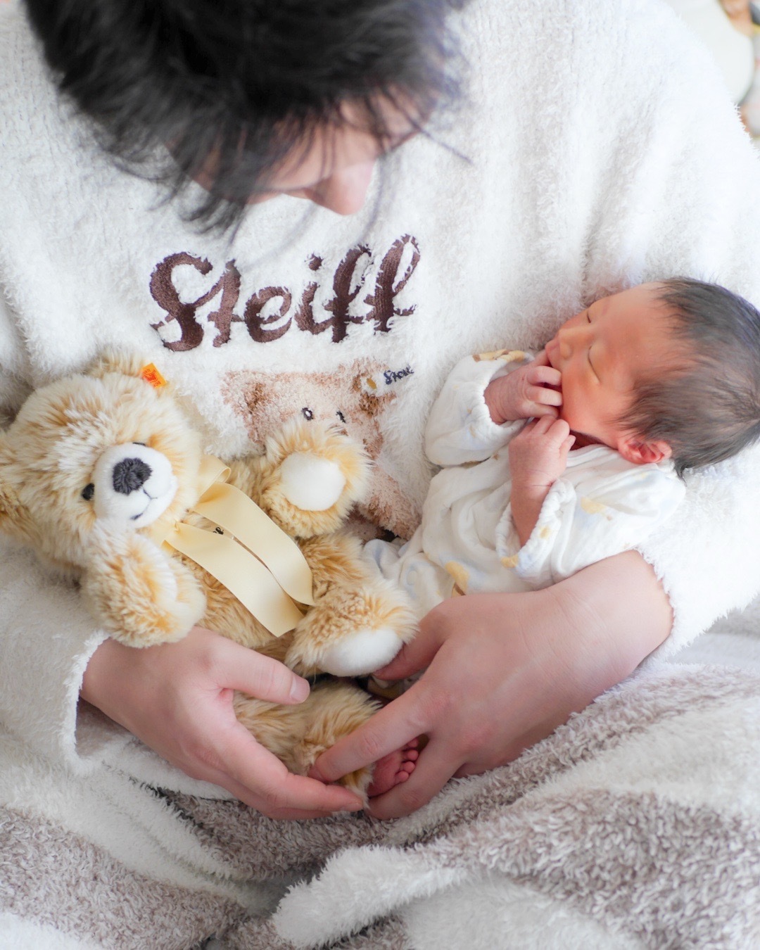 流山おおたかの森のご自宅で撮影されたニューボーンフォト。パパが新生児を抱っこし、ドイツの名品シュタイフのぬいぐるみと一緒に座っているかわいらしい一枚。家族の温かな絆と赤ちゃんの可愛らしさが感じられる特別な瞬間。